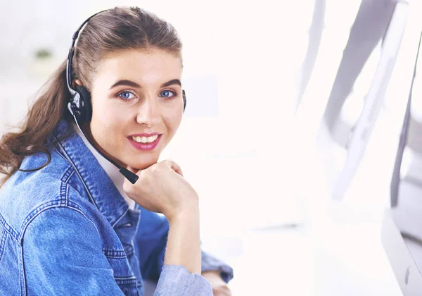 Heureuse charmante jeune femme assise et travaillant avec un ordinateur portable en utilisant un casque dans le bureau — Photo