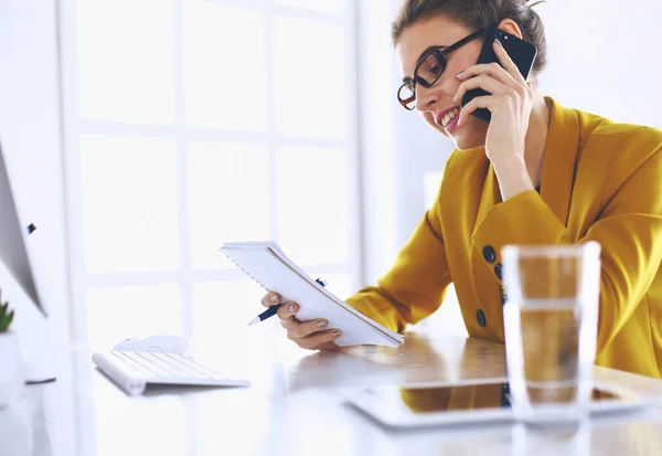 Ritratto di bella donna che chiama mentre siede sul posto di lavoro davanti al computer portatile e lavora a un nuovo progetto — Foto Stock