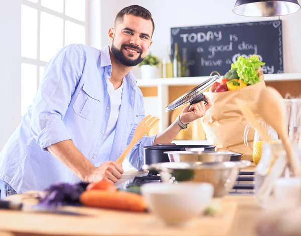 Hombre siguiendo la receta en la tableta digital y cocinar comida sabrosa y saludable en la cocina en casa —  Fotos de Stock