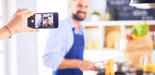 Adam ev mutfağında lezzetli ve sağlıklı yemekler hazırlıyor. Blogu için video çekiyor.. — Stok fotoğraf