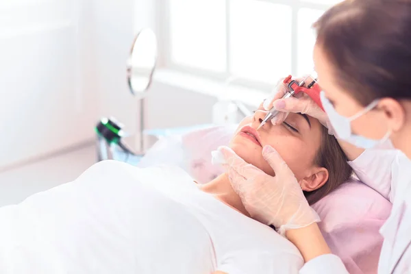 Young woman undergoing procedure of eyebrow permanent makeup in beauty salon — Stock Photo, Image