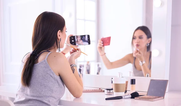 Blogueur beauté filmant tutoriel maquillage avec smartphone devant miroir — Photo