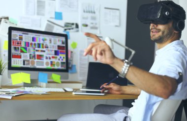 Genç erkek yazılım programcısı ofiste üç boyutlu sanal gerçeklik gözlükleriyle yeni bir uygulama test ediyor..