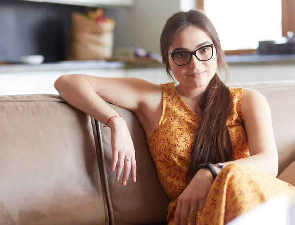 Retrato de una mujer sonriente sentada en un sofá. Estilo casual sesión de interior —  Fotos de Stock