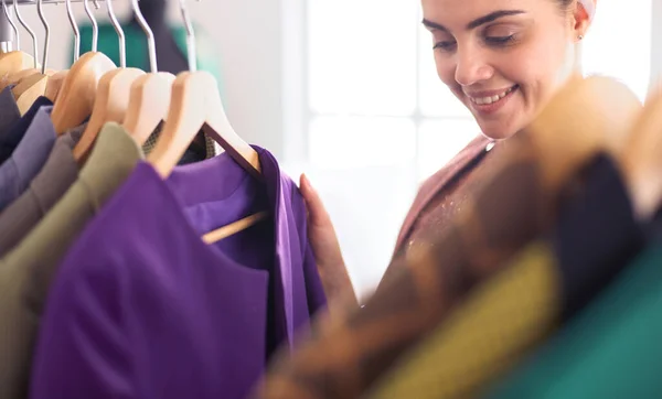 Beautiful young stylist near rack with hangers — Stock Photo, Image