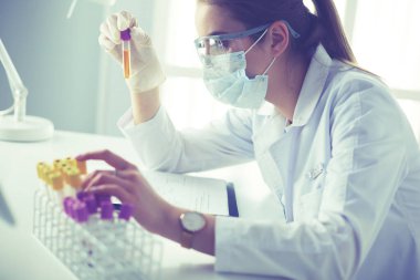 Modern laboratuvar veya hastanede plastik tıbbi tüplerle çalışan araştırmacı, doktor, bilim adamı veya laboratuvar asistanı