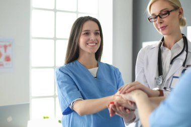 Doktorlar ve hemşireler tıbbi bir ekipte el ele tutuşuyorlar.