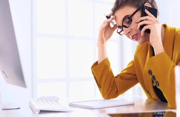 Empresaria concentrándose en el trabajo, usando computadora y celular en la oficina —  Fotos de Stock