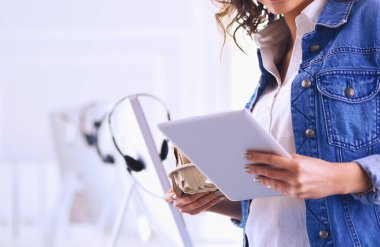 Gülümseyen kadın kahve içiyor ve kafede tablet kullanıyor.