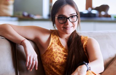 Kanepede oturan gülümseyen kadın portresi. Günlük tarz kapalı çekim.