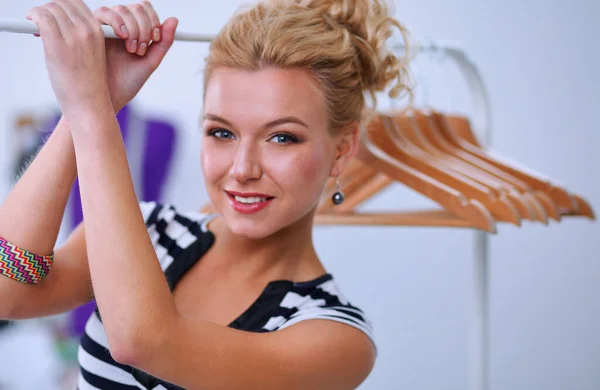 Mooie jonge stylist bij rek met hangers — Stockfoto