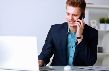 Yakışıklı genç adam dizüstü bilgisayarda oturuyor ve çalışıyor.