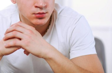 Evdeki koltukta oturan yakışıklı, kendine güvenen adam.