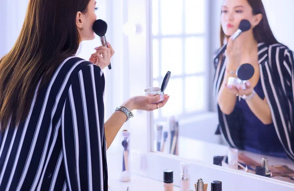 Skönhet kvinna tillämpa makeup. Vacker flicka ser i spegeln och tillämpa kosmetiska med en stor pensel — Stockfoto