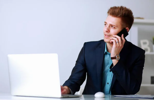 Bello giovane seduto e al lavoro sul computer portatile — Foto Stock