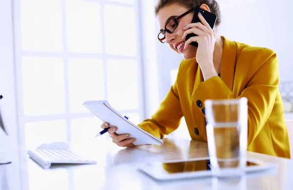 Ritratto di bella donna che chiama mentre siede sul posto di lavoro davanti al computer portatile e lavora a un nuovo progetto — Foto Stock