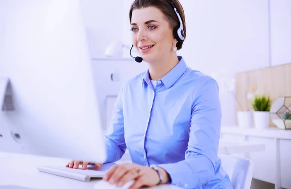 Ernstige mooie jonge vrouw die werkt als support telefoon operator met headset in het kantoor — Stockfoto