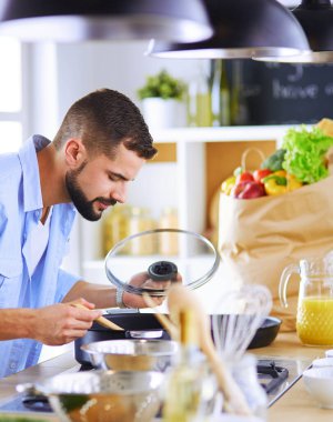 Dijital tablet ve yemek pişirme tarifine uyan bir adam evdeki mutfakta lezzetli ve sağlıklı yemekler pişiriyor.