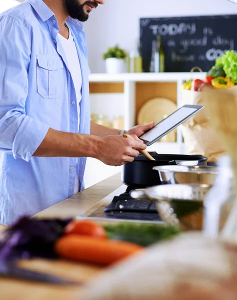 Dijital tablet ve yemek pişirme tarifine uyan bir adam evdeki mutfakta lezzetli ve sağlıklı yemekler pişiriyor. — Stok fotoğraf