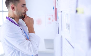 Genç ve kendinden emin erkek doktor portresi tıp ofisinde duruyor..