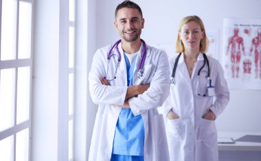 Yakışıklı doktor genç bayan doktorla konuşuyor ve ofisinde otururken notlar alıyor..