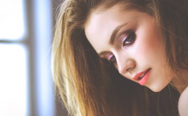 Güzel genç bir kadın beyaz yatakta yatıyor.