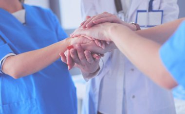 Doktorlar ve hemşireler tıbbi bir ekipte el ele tutuşuyorlar.