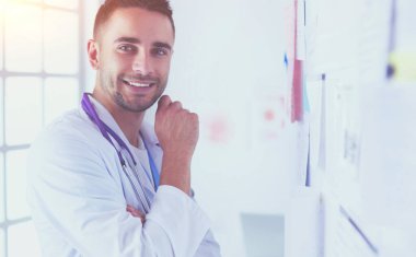 Genç ve kendinden emin erkek doktor portresi tıp ofisinde duruyor..