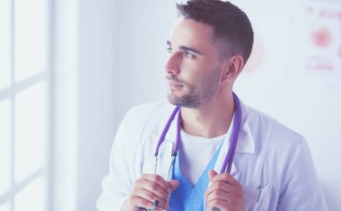 Genç ve kendinden emin erkek doktor portresi tıp ofisinde duruyor..