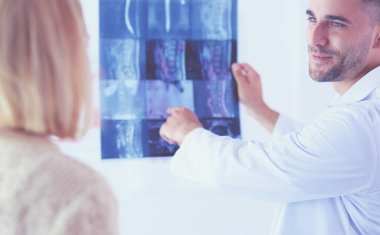 Yakışıklı doktor genç bayan hastasıyla konuşuyor ve ofisinde otururken notlar alıyor..