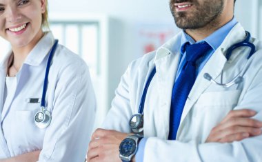 Tıp bürosunda kollarını kavuşturmuş kendine güvenen doktorların portresi.