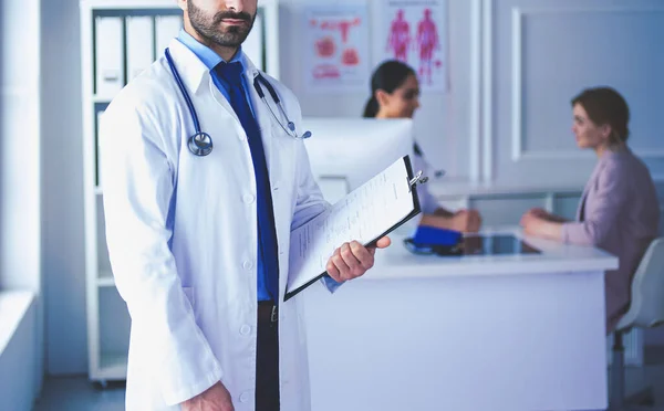 Sonriente médico de pie frente a su equipo y paciente — Foto de Stock