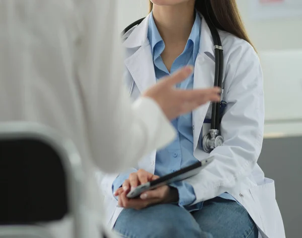 Doktorn och patienten diskuterar något när de sitter vid bordet. Medicin och hälsovård — Stockfoto