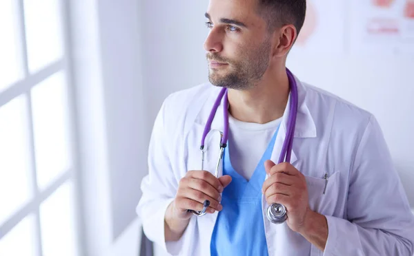 Retrato médico masculino joven y confiado de pie en el consultorio médico. —  Fotos de Stock