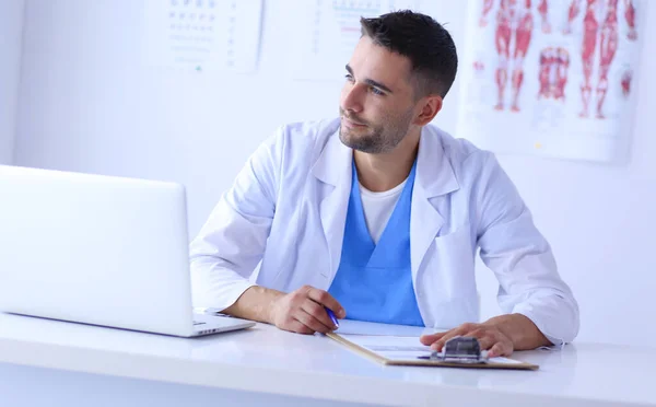 Porträt eines männlichen Arztes mit Laptop am Schreibtisch in der Arztpraxis. — Stockfoto