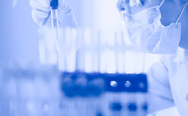 A medical or scientific researcher or doctor looking at a test tube of liquid green solution in a laboratory — Stock Photo, Image