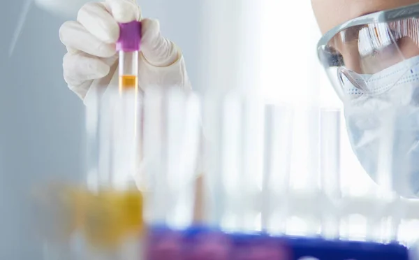 Um pesquisador médico ou científico ou um médico olhando para um tubo de ensaio de solução líquida verde em um laboratório — Fotografia de Stock