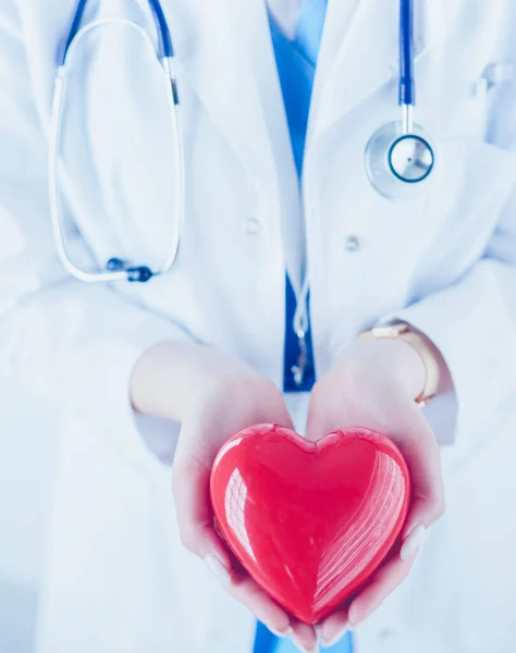 Doctora con estetoscopio sosteniendo el corazón, sobre fondo claro — Foto de Stock