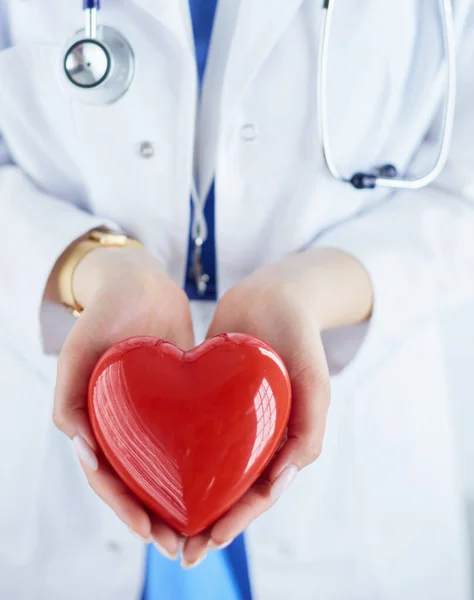 Female doctor with stethoscope holding heart, on light background — Stock Photo, Image