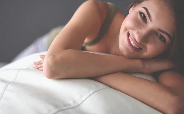 Closeup of a smiling young woman lying on couch — Stock Photo, Image