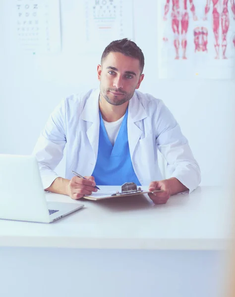 Porträt eines männlichen Arztes mit Laptop am Schreibtisch in der Arztpraxis. — Stockfoto