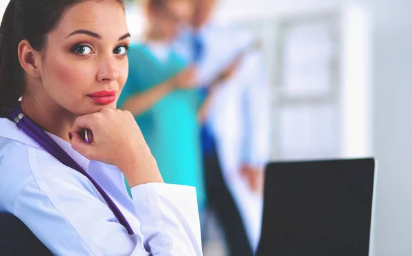 Hermosa joven sonriente doctora sentada en el escritorio — Foto de Stock