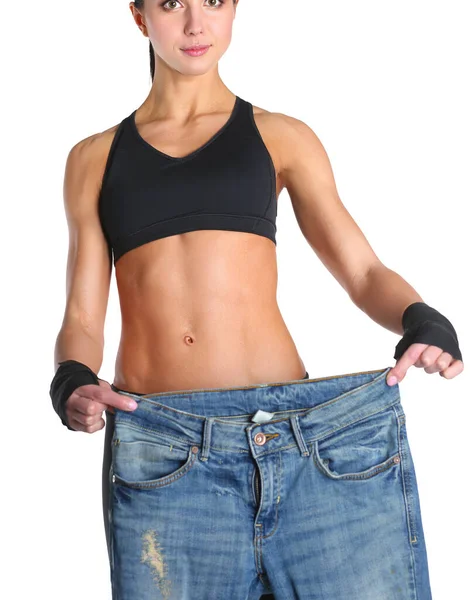 Młoda kobieta fitness pokazuje, że jej stare dżinsy — Zdjęcie stockowe