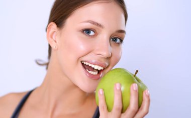 Mutlu genç kadın elma yiyor, beyaz arka planda soyutlanmış.