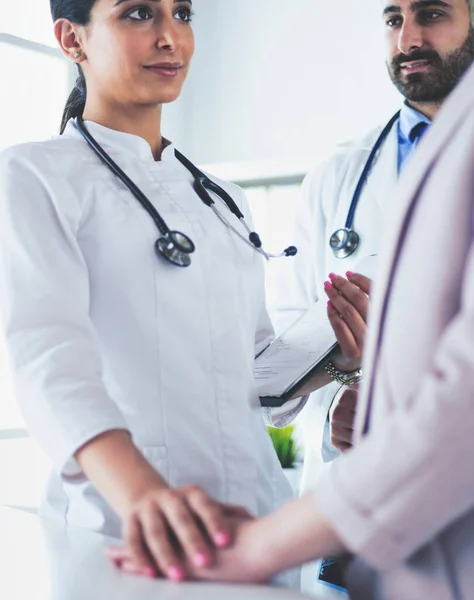 Médico bonito está conversando com jovem paciente do sexo feminino e fazendo anotações enquanto está sentado em seu escritório — Fotografia de Stock