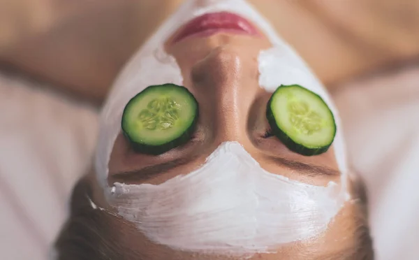 Mulher bonita recebendo máscara facial de pepino no salão de beleza — Fotografia de Stock