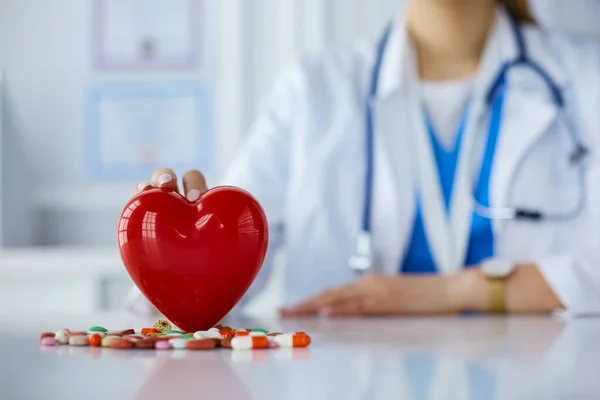 医師で白いコートで聴診器を保持薬とプラスチック心臓は白い上に隔離 — ストック写真