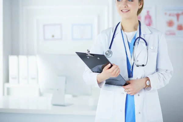 Smiling female doctor with a folder in uniform standing — Stok Foto
