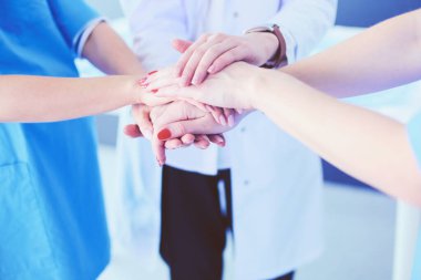 Doktorlar ve hemşireler tıbbi bir ekipte el ele tutuşuyorlar.