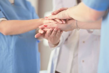 Doktorlar ve hemşireler tıbbi bir ekipte el ele tutuşuyorlar.